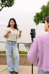Young woman creating video content with friend assistance