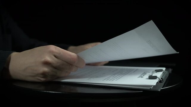 Ripping contract papers on black. A view of woman hands ripping her contracts documents on the table because of police problems on the black background