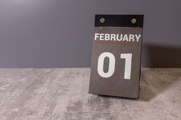 Wooden block calendar with date February 01 on pink blue backround.