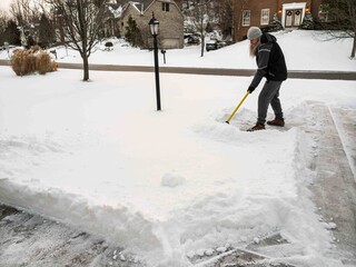 Active man clearing snow from residential driveway on winter day