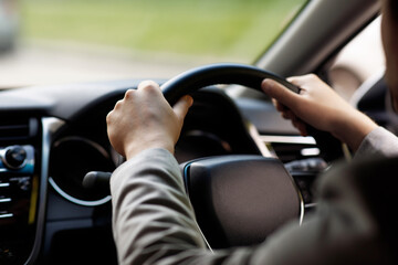 Sale and rental transport. Driver holding steering wheel sitting in new auto, enjoy road trip to work. Young businessman drives modern new car on road, view in cabin, cropped, close up, free space