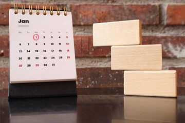 Stack of wooden blocks and January calendar with brick wall background