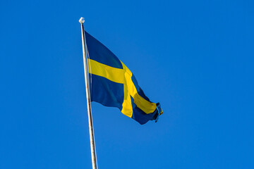 The national flag of Sweden, flying on a flagstaff against a blue sky