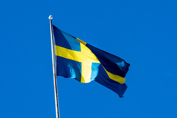 The national flag of Sweden, flying on a flagstaff against a blue sky