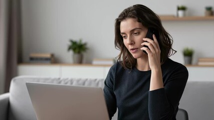 Smiling Young Woman Engaged in a Phone Call While Working on Laptop at Modern Home Office Desk