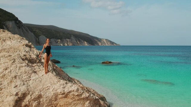 Woman enjoying scenic Kefalonia coastline with turquoise sea and cliffs under clear summer light