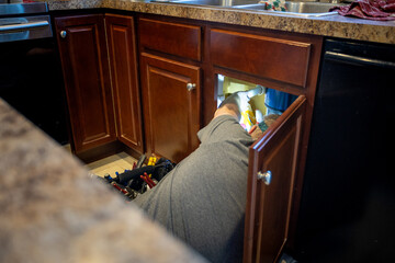 handy man fixing plumbing under kitchen sink, tool bag and knowledge of home fixes. 
