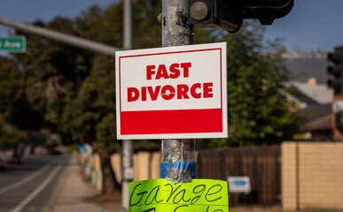 A sign stating Fast Divorce on a light pole in a suburban neighborhood