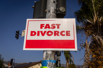 A sign stating Fast Divorce on a light pole in a suburban neighborhood