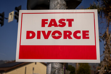 A sign stating Fast Divorce on a light pole in a suburban neighborhood
