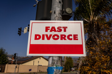 A sign stating Fast Divorce on a light pole in a suburban neighborhood