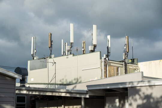 Mobile phone towerGMS cellular communication towers mounted on the rooftop of a commercial shop building, featuring multiple antennas and transmission equipment against an urban skyline.