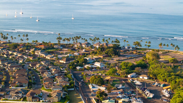 Aerial view of Lahaina landscape in Maui, Hawaii wildfire aftermath showing coastline, roads, homes, and sailboats in ocean during morning light