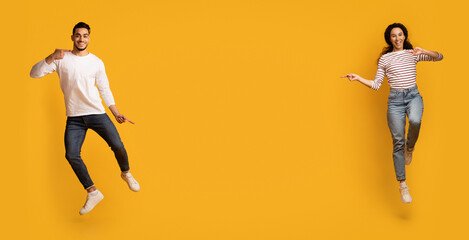 Cool Offer. Excited Joyful Arab Couple Jumping And Pointing In The Middle, Happy Cheerful Middle...