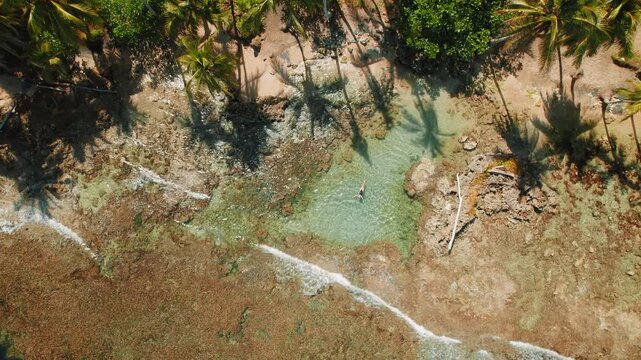 Solo traveler woman floating in tidal pool by palm beach Playa Cocles in Costa Rica