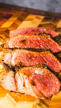 Topside beef roast coated in flavorful rub, roasted rare and juicy inside, presented on a wooden board. Tender, succulent, and beautifully sliced for serving. Perfect for special occasions.