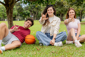 Friends on grass making the I Love You sign language gesture