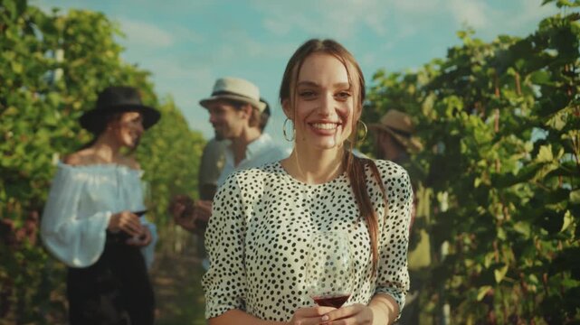 Vineyard woman smiling, Cheerful woman in polkadot blouse relishes wine among friends in scenic vineyard setting