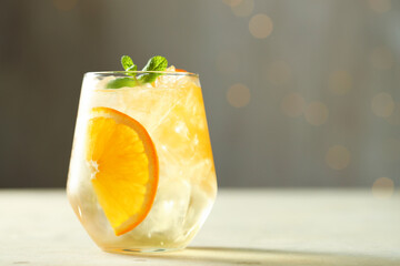 Refreshing spritzer cocktail on light table against grey background with bokeh effect, closeup. Space for text