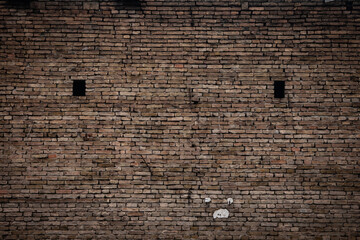 Old brick wall with weathered texture and visible aging. The surface shows uneven masonry and worn material commonly found on historic or older buildings.