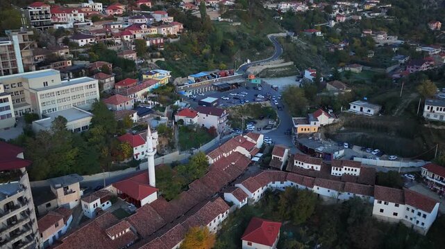 Aerial video of Kruj&euml; city centre with Kruja Bazaar, mosque, and hillside homes under soft evening light.