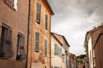 Facade of typical Proven&ccedil;al village houses in Collobrieres, france, with pastel walls and green shutters. The composition shows French real estate character and Mediterranean vernacular architecture.