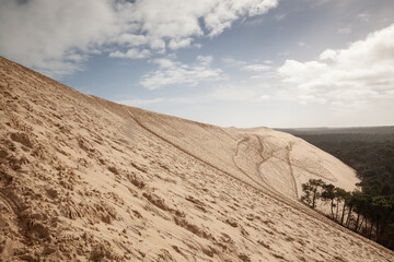 View of the Dune du Pyla in France, showing vast sand slopes under a partly cloudy sky. Pilat, or Pyla Dune is the biggest sand dune in Europe, in Arcachon Bay, in Aquitaine.