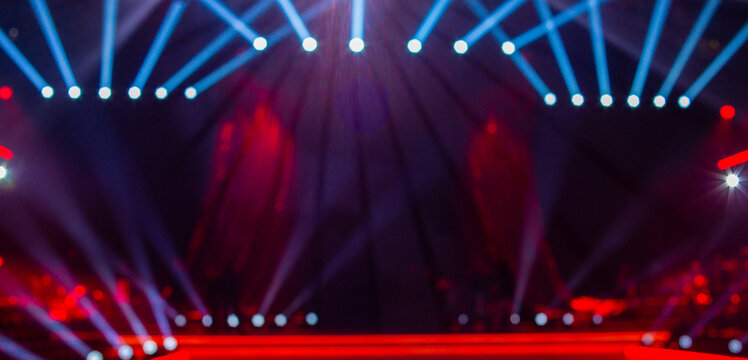 Abstract blurred background with a stage, spotlights, and red curtains