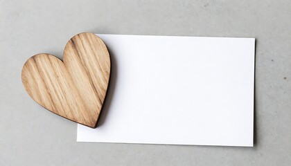 A rustic wooden heart resting on a blank white note card, ready for a special message