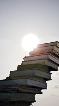 Concept idea stack of books on sky sun set dawn beautiful background. 3D animation. 4K. Vertical.