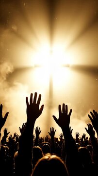 A silhouette of a crowd with hands raised in supplication towards a bright, illuminated cross against a smoky, golden sky, evoking a sense of spiritual awe.