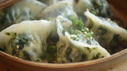 A tantalizing close-up shot captures freshly steamed savory dumplings resting invitingly in a traditional bamboo steamer, adorned with vibrant chopped green onions and toasted sesame seeds. Wisps of s