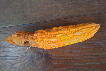 Mature bitter gourd turning red-orange on the wood table 
