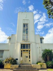 A lady and huge concrete building, a memorial tower in forest under blue sky in New Zealand.