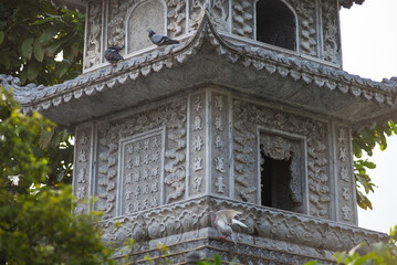 Fototapeta premium Gray building with a birdhouse on top. The birds are perched on the roof. The building has a lot of detail and looks like it is from a different time period