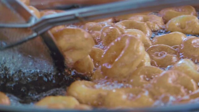 Fresh Turkish doughnuts being fried in hot oil at a market