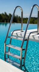 Polished stainless steel ladder descends into bright blue water next to a white diving platform under a clear sky