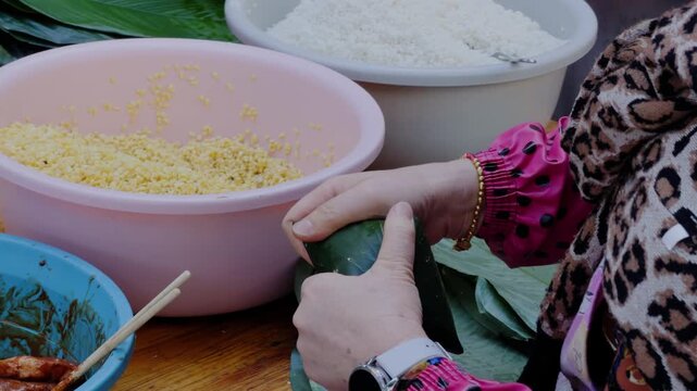 An aunt is wrapping zongzi, a traditional food for the Chinese Dragon Boat Festival.