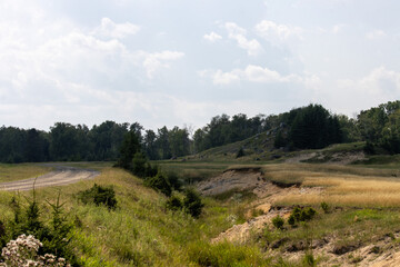 Fototapeta premium Canada, Quebec, 09 August 2025 : Winding gravel road through grassy fields and trees under sky