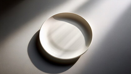 Minimalist White Ceramic Plate Positioned At An Angle On A Light Gray Surface With Soft Shadows Creating An Elegant Presentation Background