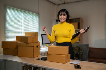 Online seller checking parcel boxes using digital tablet and smiling at home office