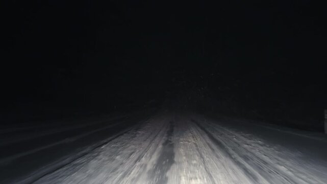 Evening winter journey, Driving along snowy paths under dark sky with headlights piercing through