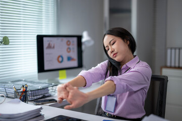 Office worker stretching arms at desk after work on computer