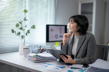 Asian businesswoman working with financial documents and thinking about new projects in modern office