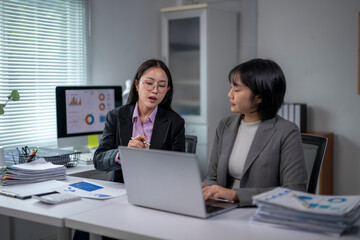 Businesswomen working together using laptop in office discussing charts and data analysis