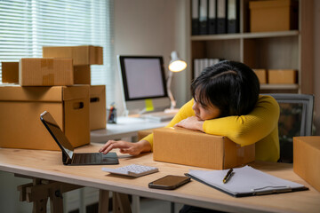 Tired asian woman running sme business feeling bored and leaning on parcel box