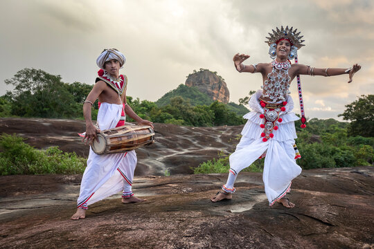 SIGIRIYA, SRI LANKA - DECEMBER 04, 2025 : A Gatabera Player (Getaberakaruwo) and a Ves Dancer or Up Country Dancer perform in front of Sigiriya Rock in Sri Lanka.