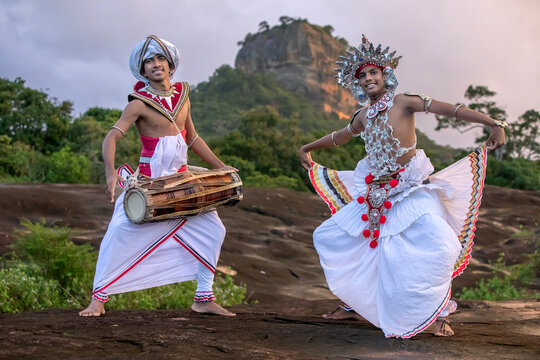 SIGIRIYA, SRI LANKA - DECEMBER 04, 2025 : A Gatabera Player (Getaberakaruwo) and a Ves Dancer or Up Country Dancer perform in front of Sigiriya Rock in Sri Lanka.