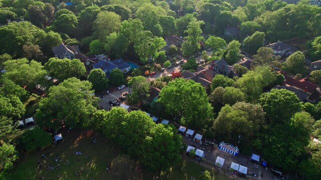 A sunset aerial over Inman Park festival, a popular springtime event in a historic Atlanta, Georgia neighborhood nestled within a vibrant urban tree canopy and scenic parks and streets.
