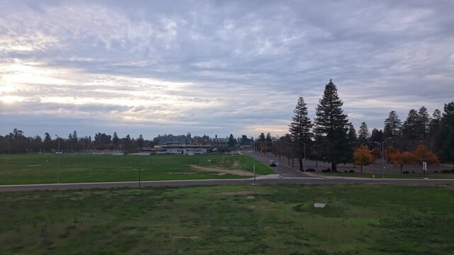 Overhead drone views present the California State Stanislaus campus beneath an overcast dusk sky, emphasizing architectural details, tree-lined paths, and a reflective evening mood.